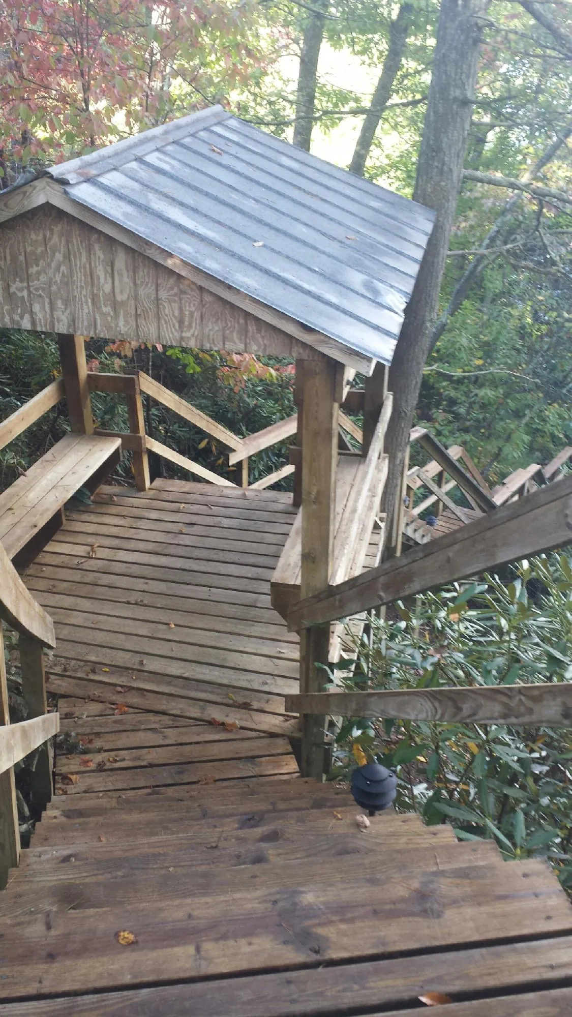 Metal roofed shelter over wooden steps on a wooded walkway — Skylight Repair & Installation work by our crew in Kenyon